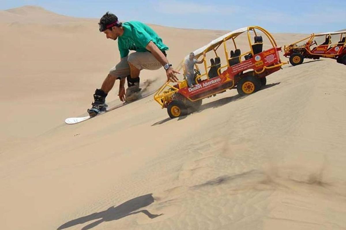 um homem em uma prancha de snowboard no deserto com um jipe