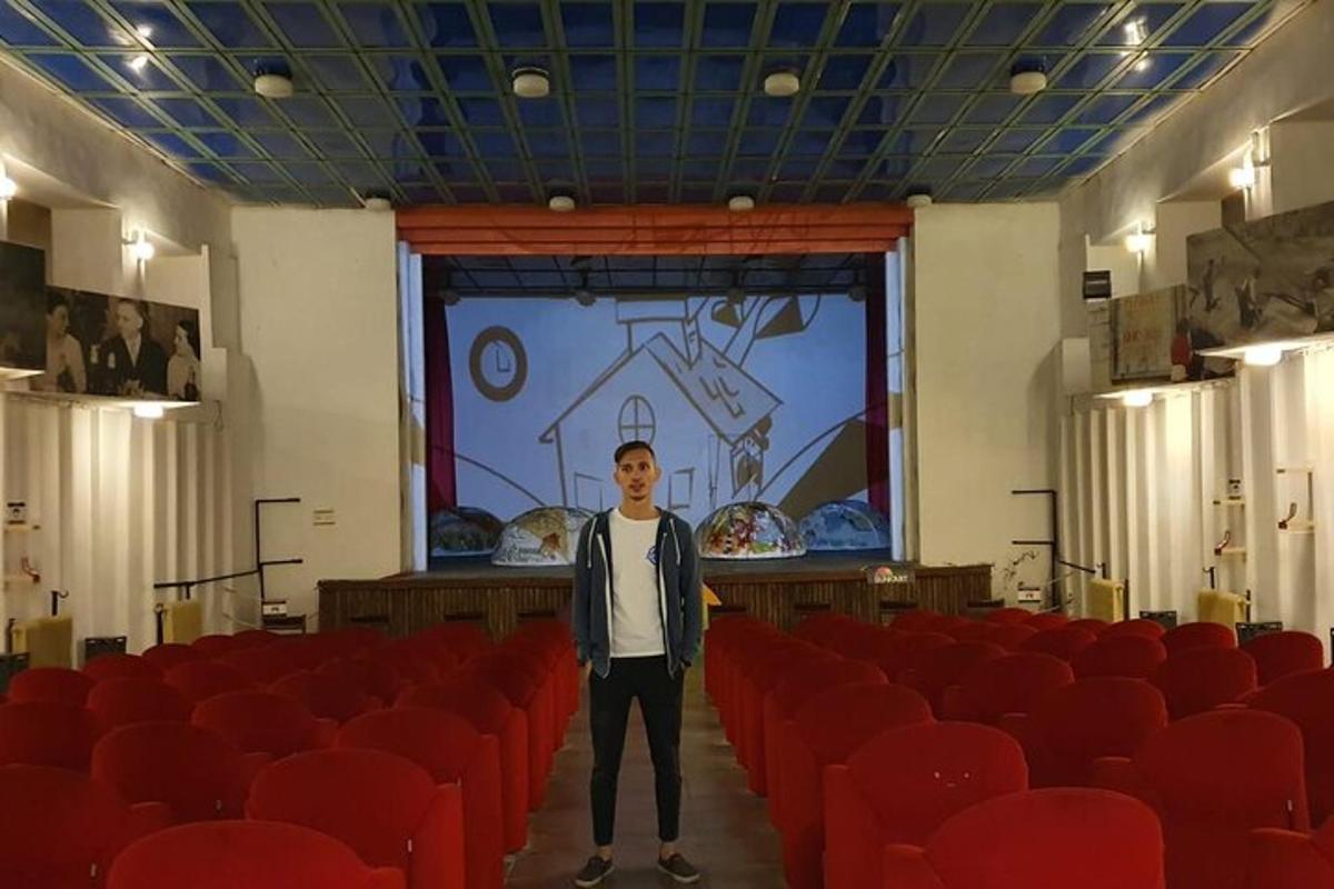 muž stojící uprostřed místnosti s červenými židlemi