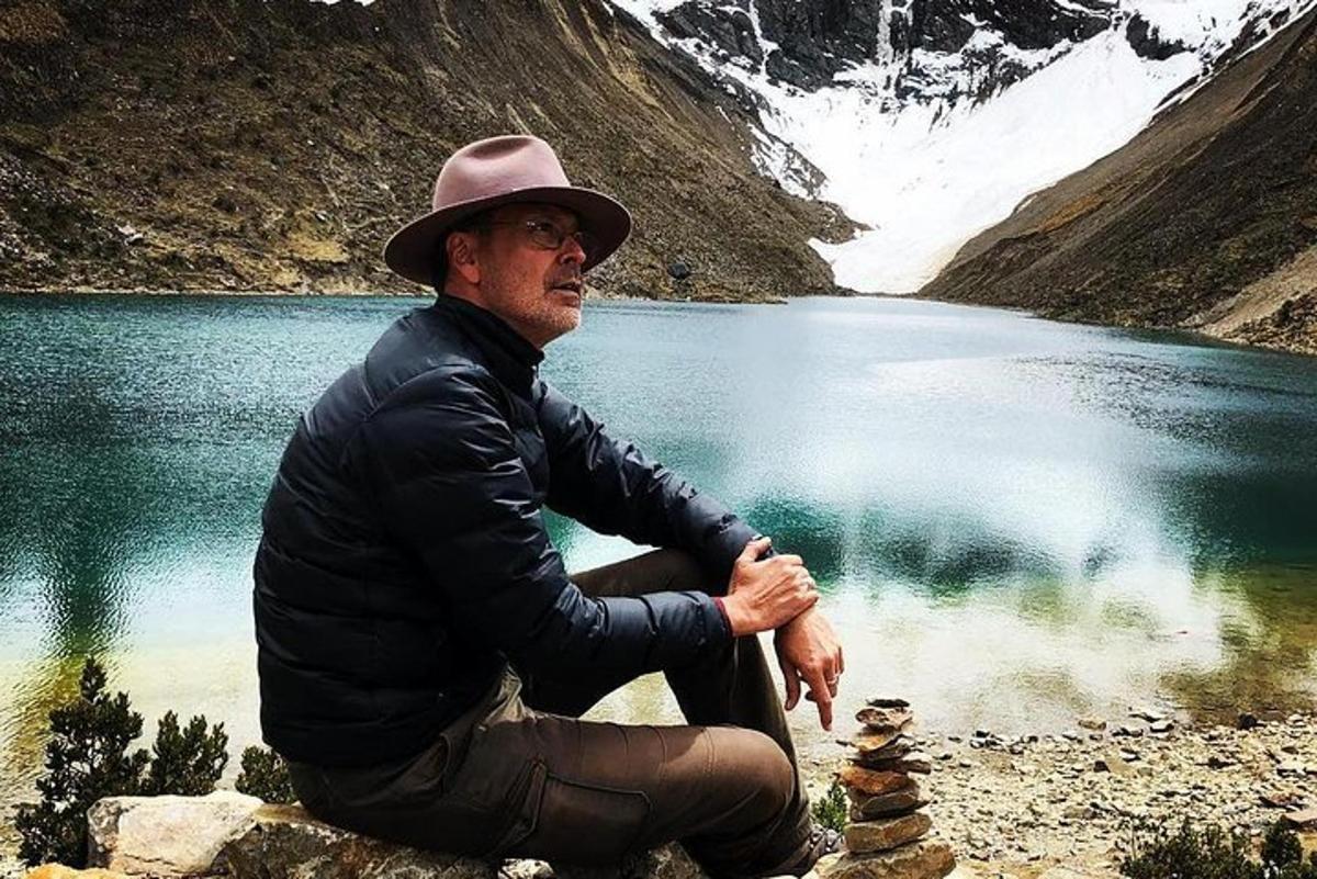um homem de chapéu sentado perto de um lago
