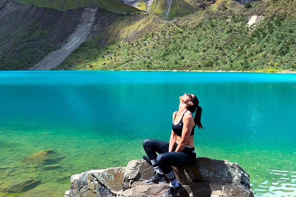 uma mulher sentada em uma rocha em frente a um lago