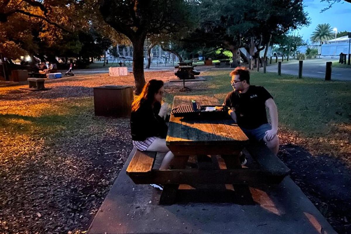 două persoane așezate la o masă de picnic într-un parc