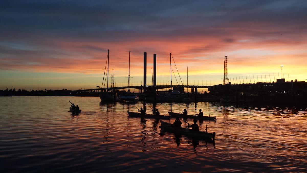 a group of people in boats in the water at sunset