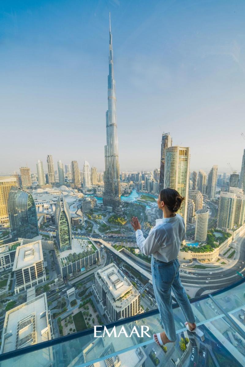 a woman standing on the edge of a tower looking at a city