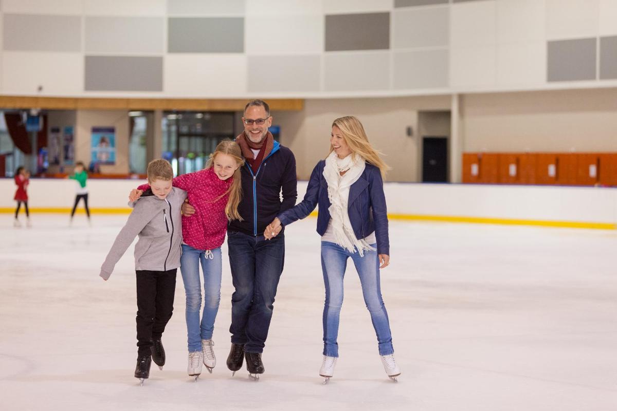 Un hombre, dos mujeres y un niño patinando sobre el hielo.