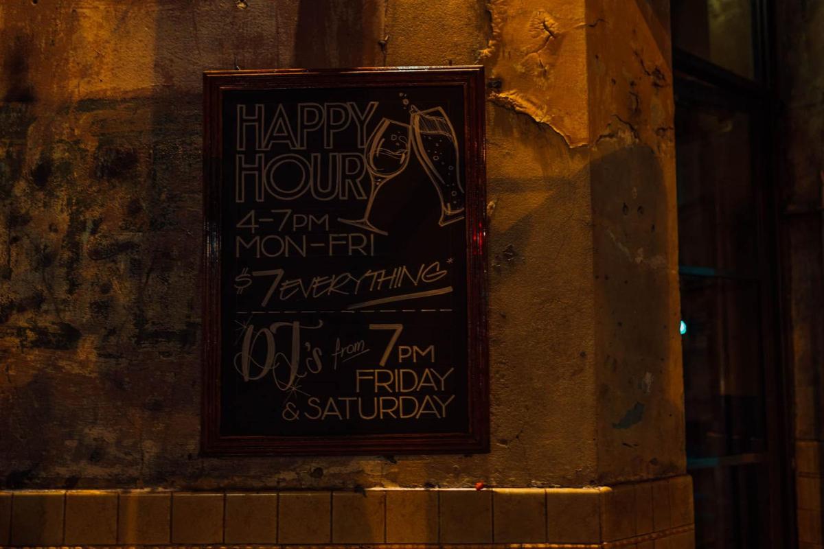 a sign on the side of a wall with a happy hour sign