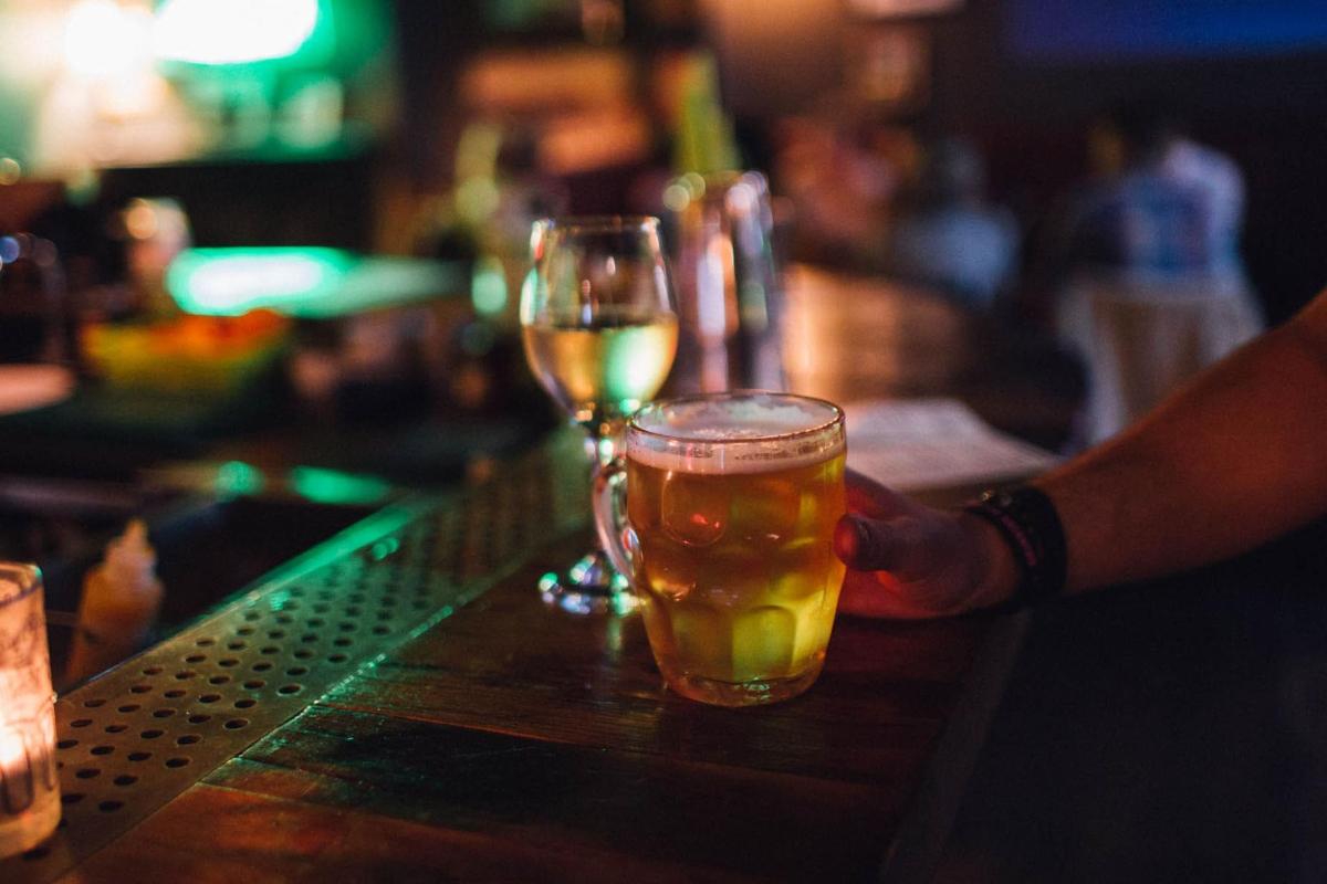 seseorang yang memegang segelas bir di atas bar