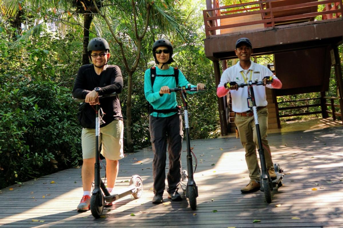 tres persones van amb patinets per un pont