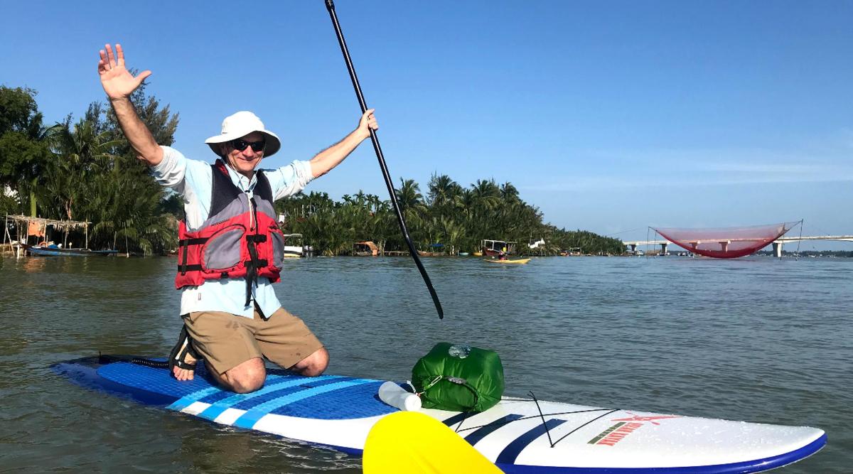 Muž sedí na paddleboardu ve vodě
