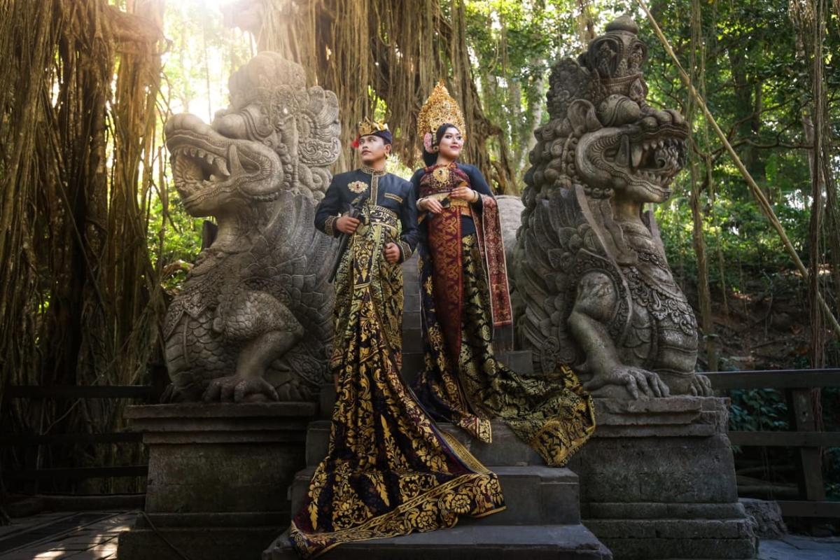 two people standing on a statue in a forest