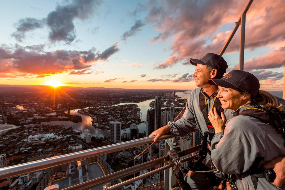 Dos personas de pie en lo alto de una torre mirando la puesta de sol.