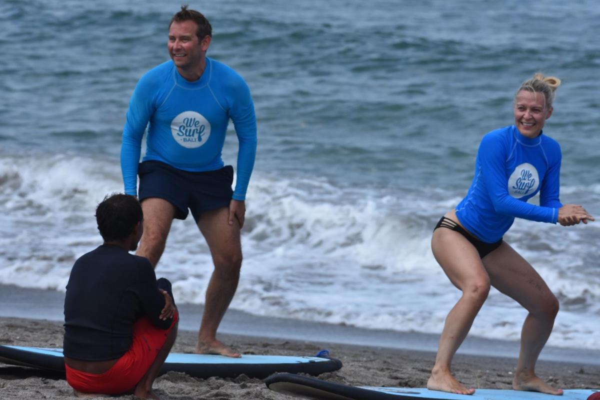 sekumpulan orang berdiri di atas papan luncur di pantai