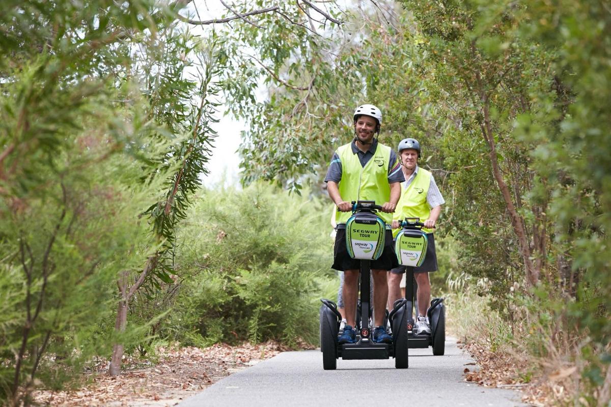 două persoane care călătoresc pe Segway-uri pe un drum