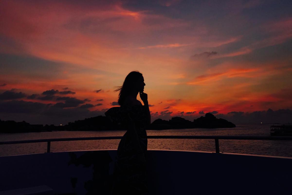 a woman standing in front of a sunset