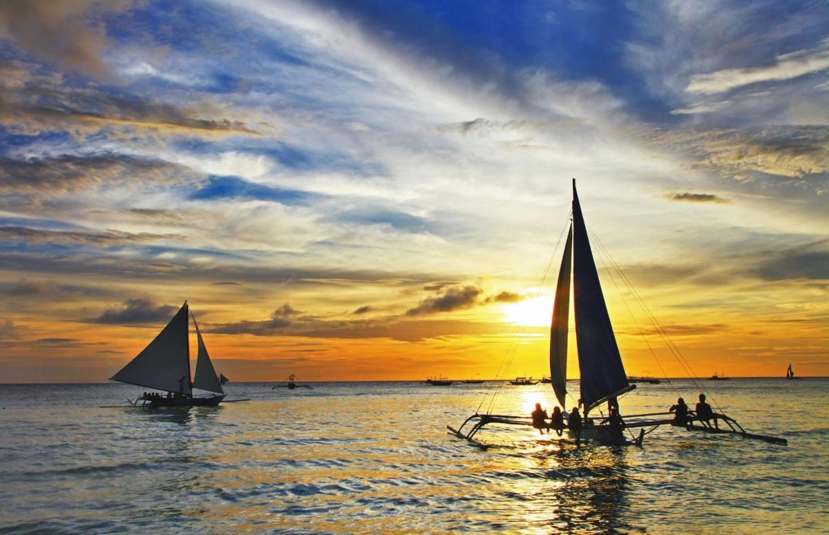 a group of people on a beach with sailboats