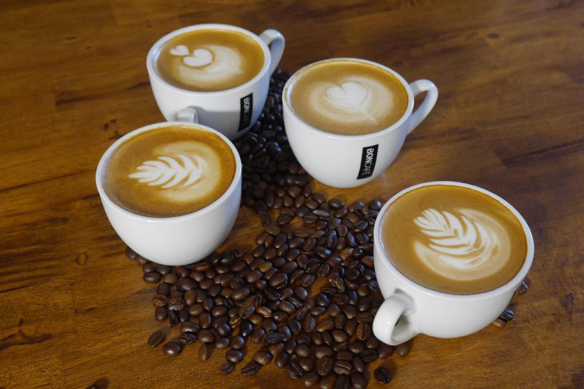 quattro tazze di caffè su un tavolo con chicchi di caffè