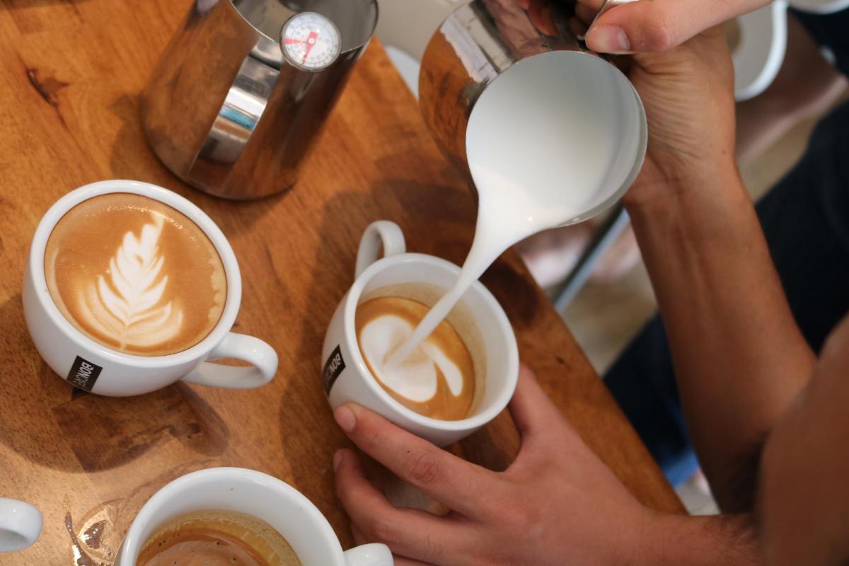 una persona che versa il latte in una tazza di caffè
