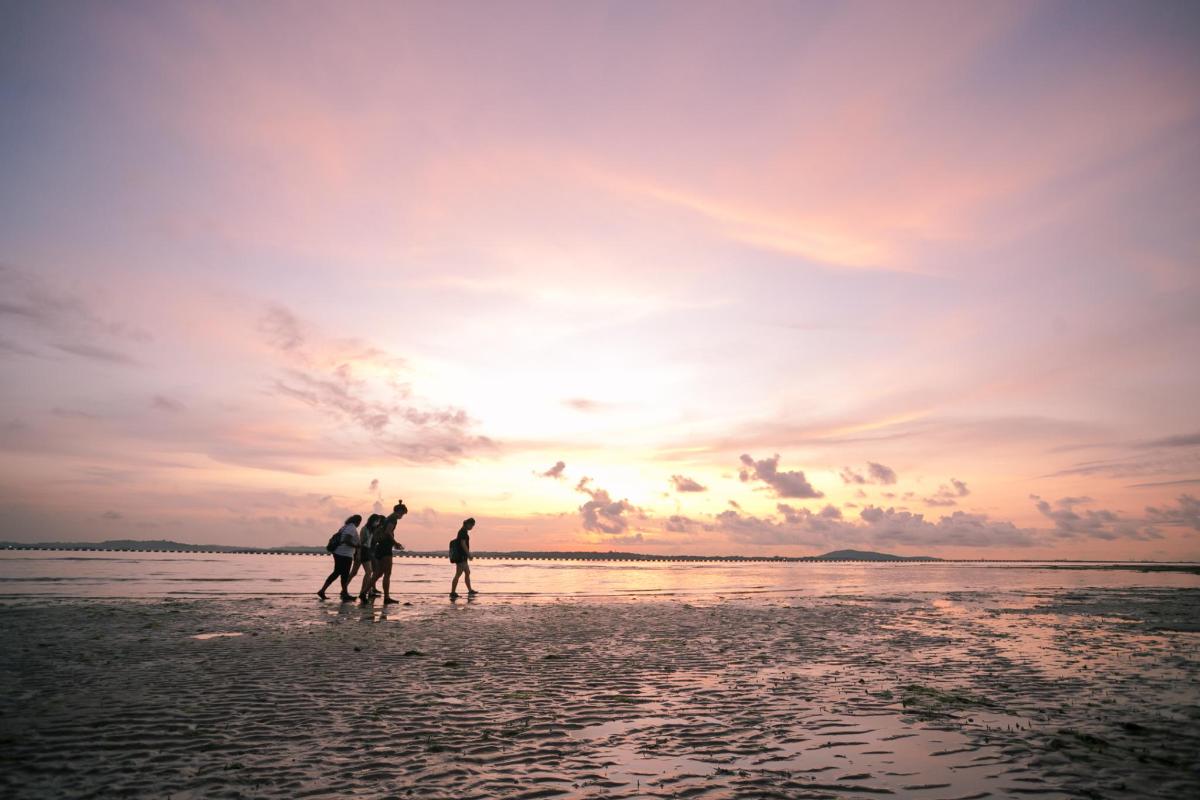 three people walking on the beach at sunset
