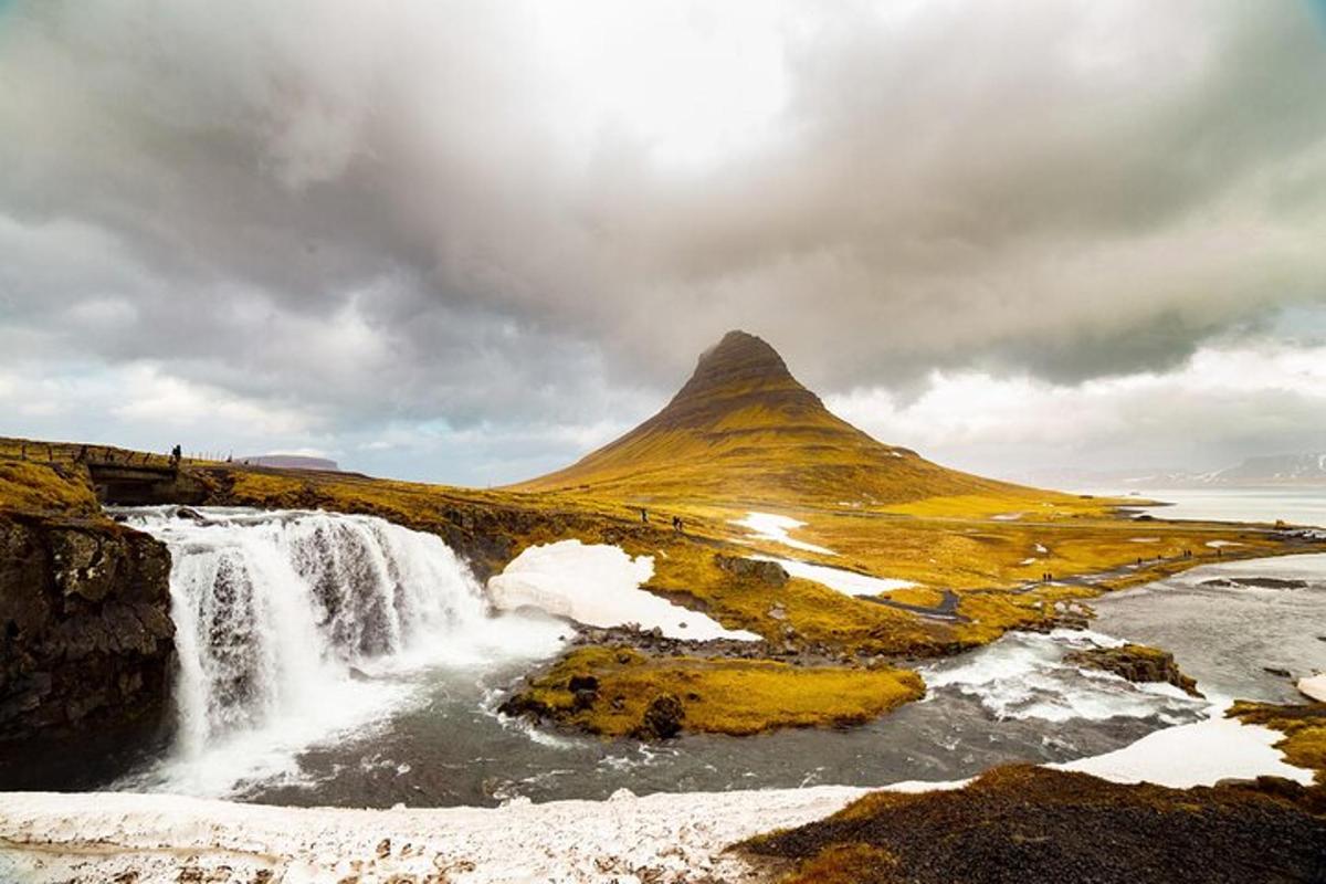 una cascada en un campo con una montaña al fondo