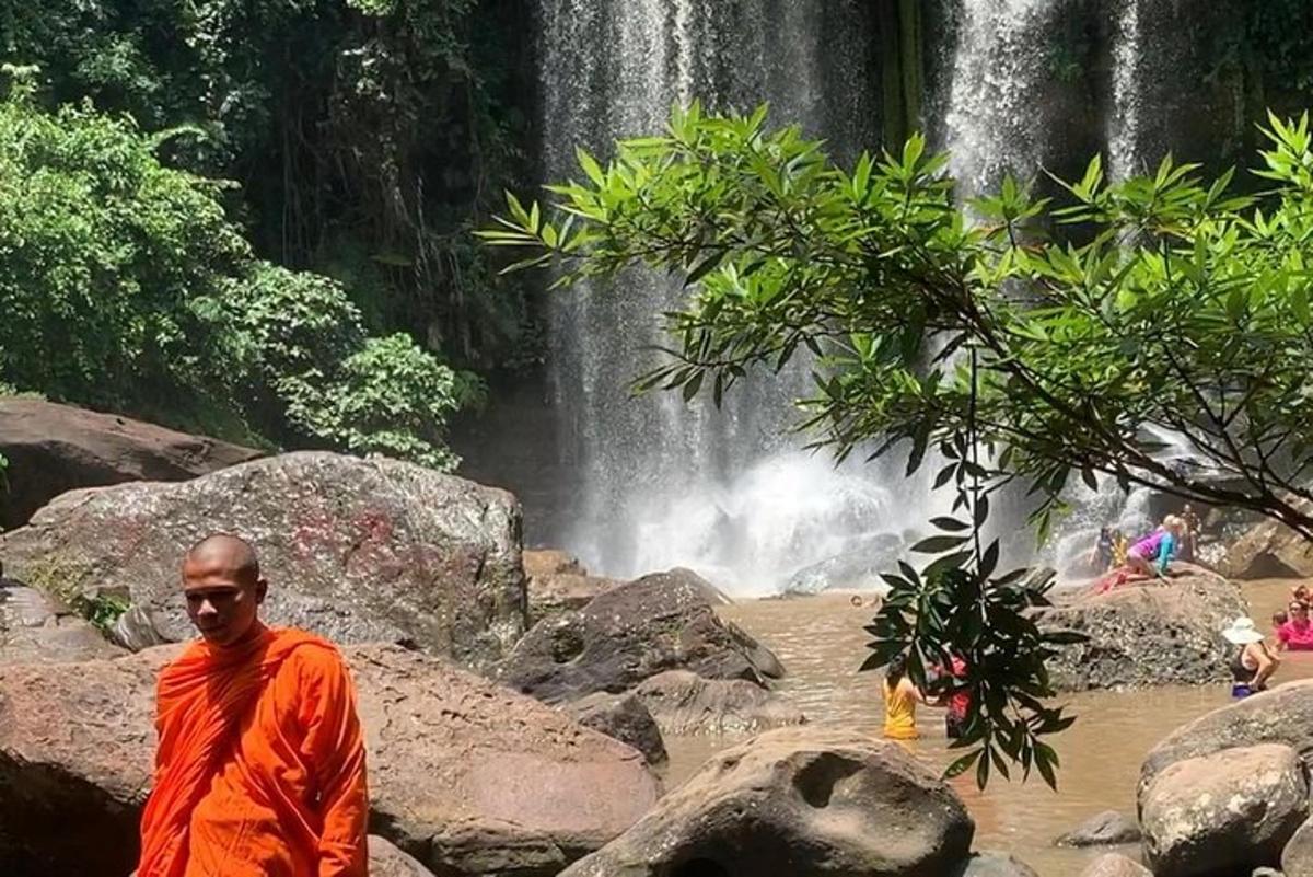 seorang lelaki berjubah oren berdiri di hadapan air terjun