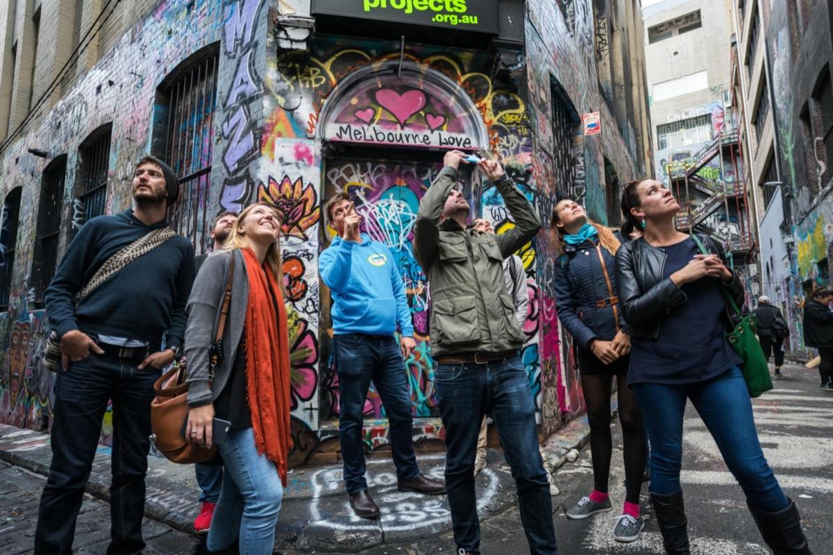 a group of people standing in front of a wall with graffiti