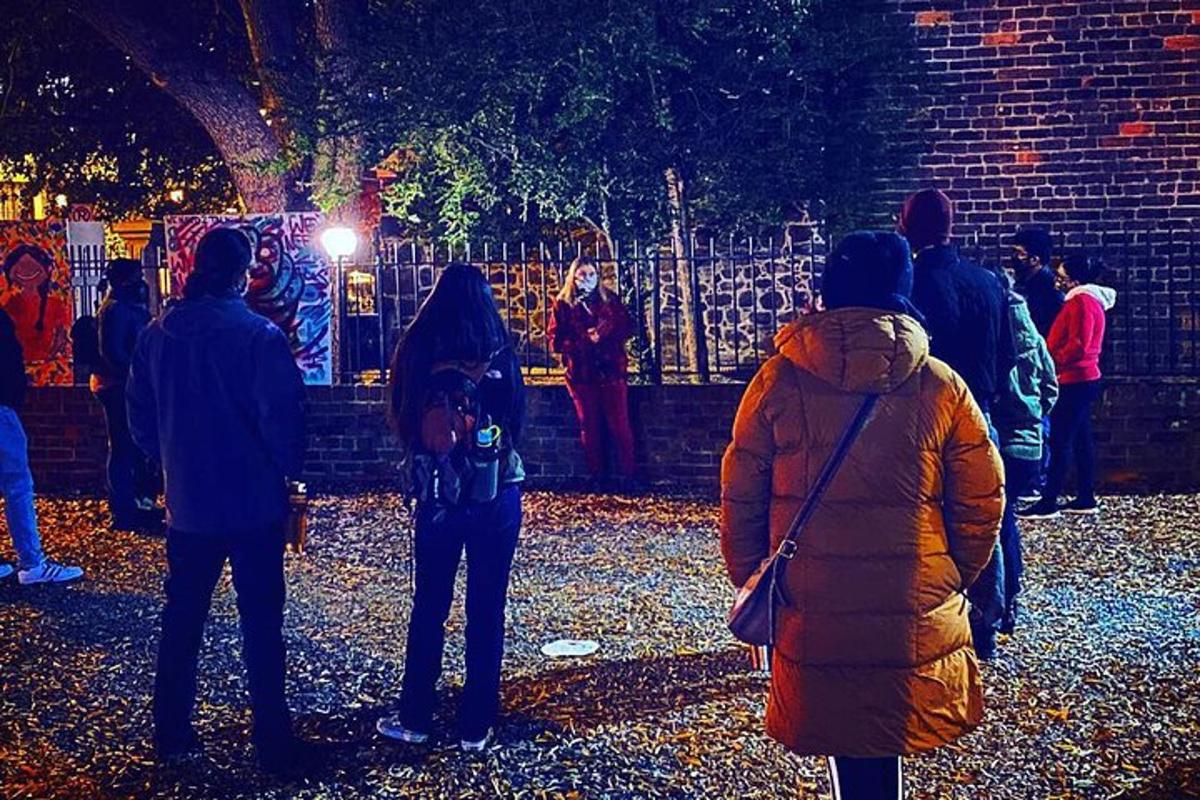 a group of people standing near a fence at night
