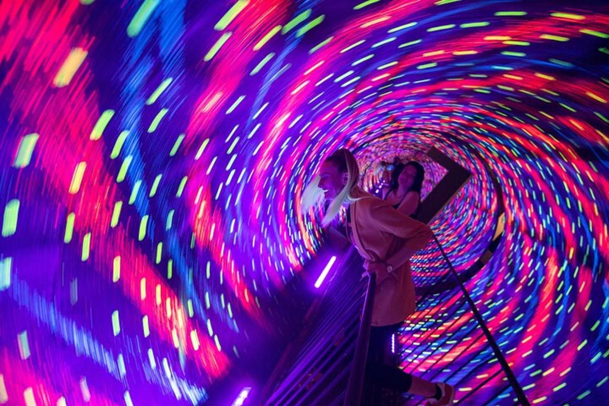 two people standing in a tunnel of colored lights