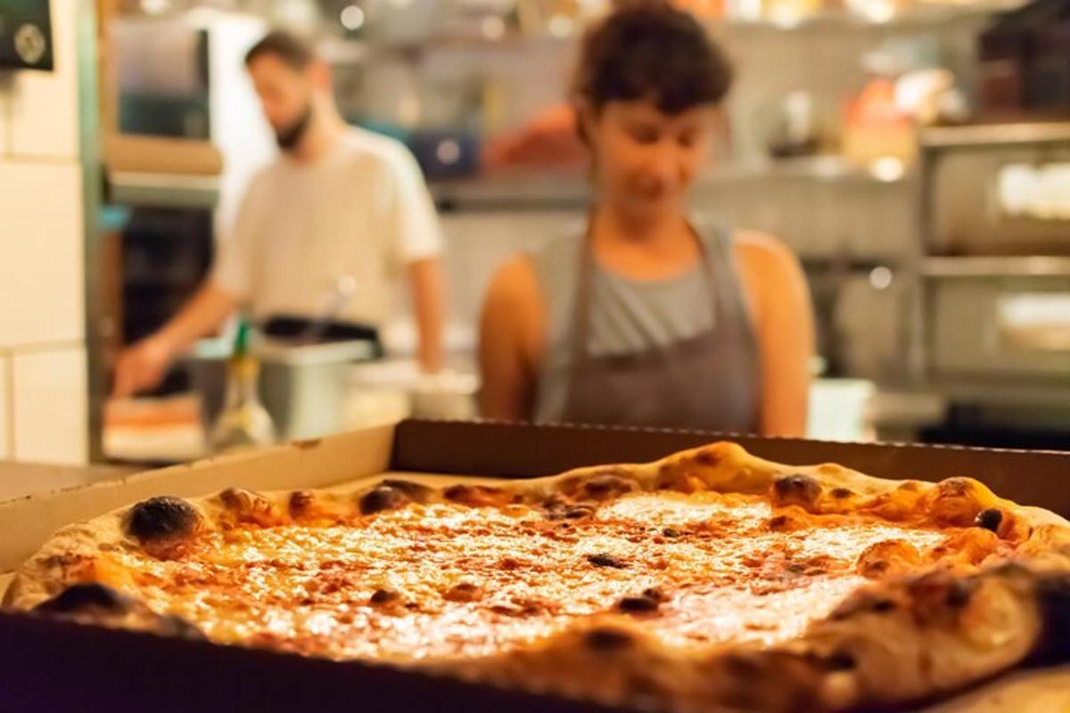 a person in a kitchen with a pizza in a box