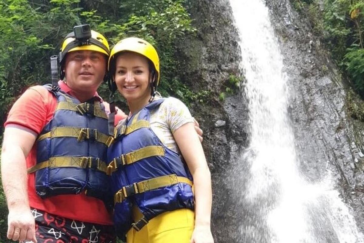 a man and a woman standing in front of a waterfall