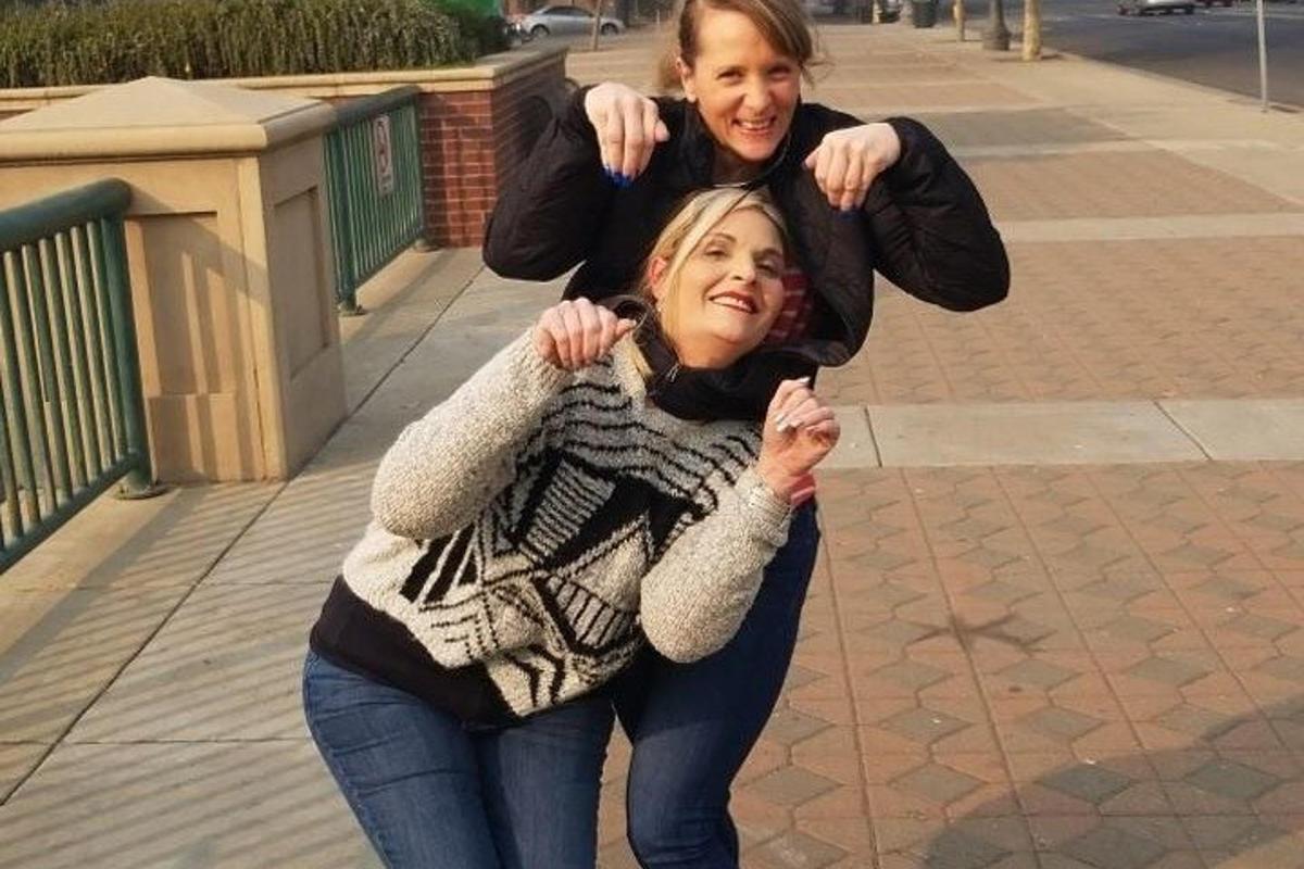 Дві дівчини позують для фотографії на тротуарі