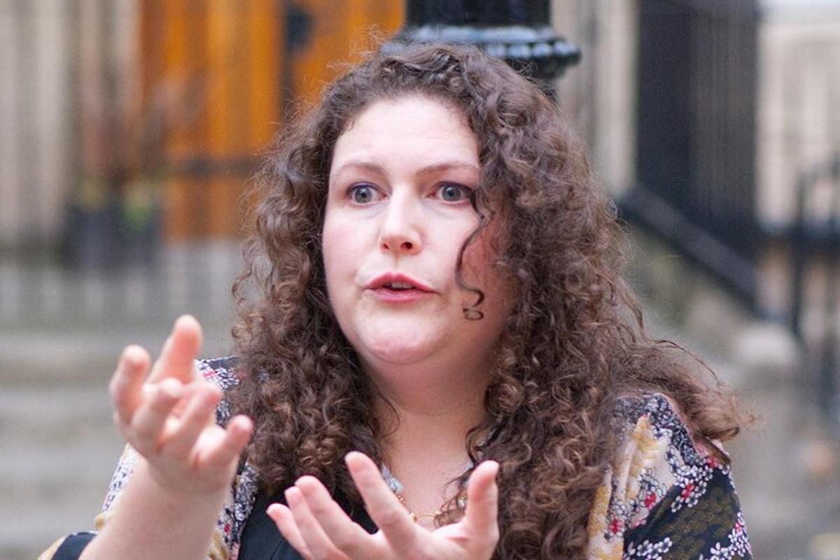 žena s kudrnatými vlasy stojící se zdviženýma rukama