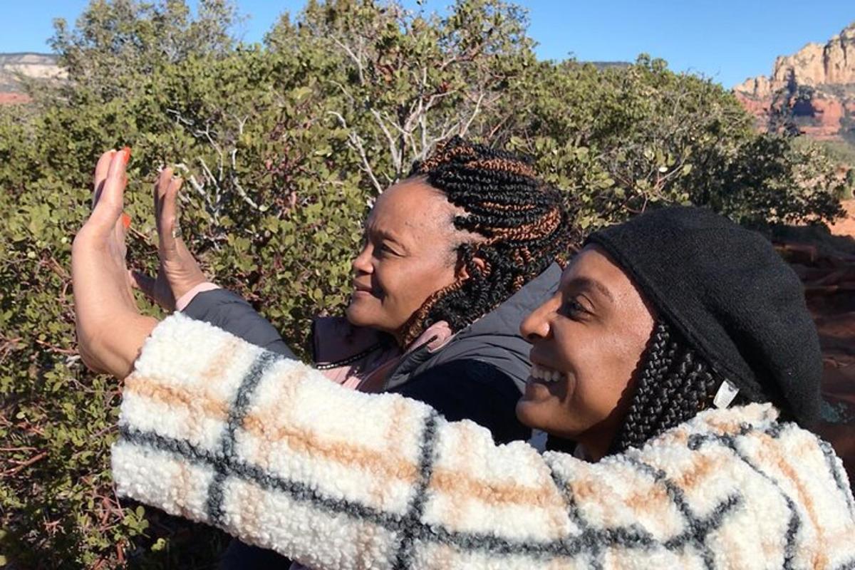Dos mujeres sentadas en un arbusto con las manos en el aire