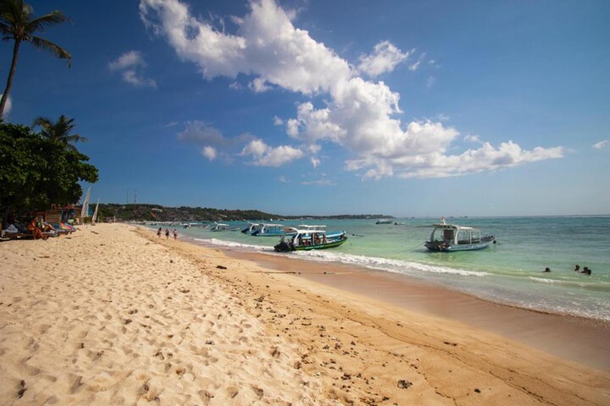 una spiaggia con barche nell'oceano e persone in acqua
