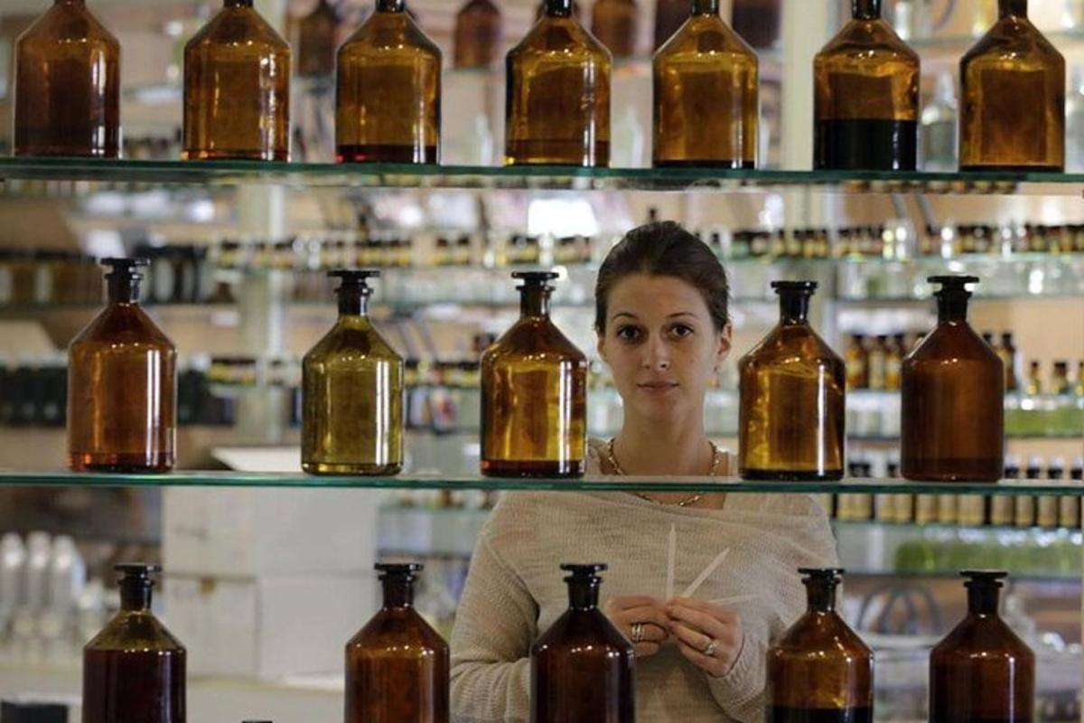Una mujer parada frente a estantes de botellas.