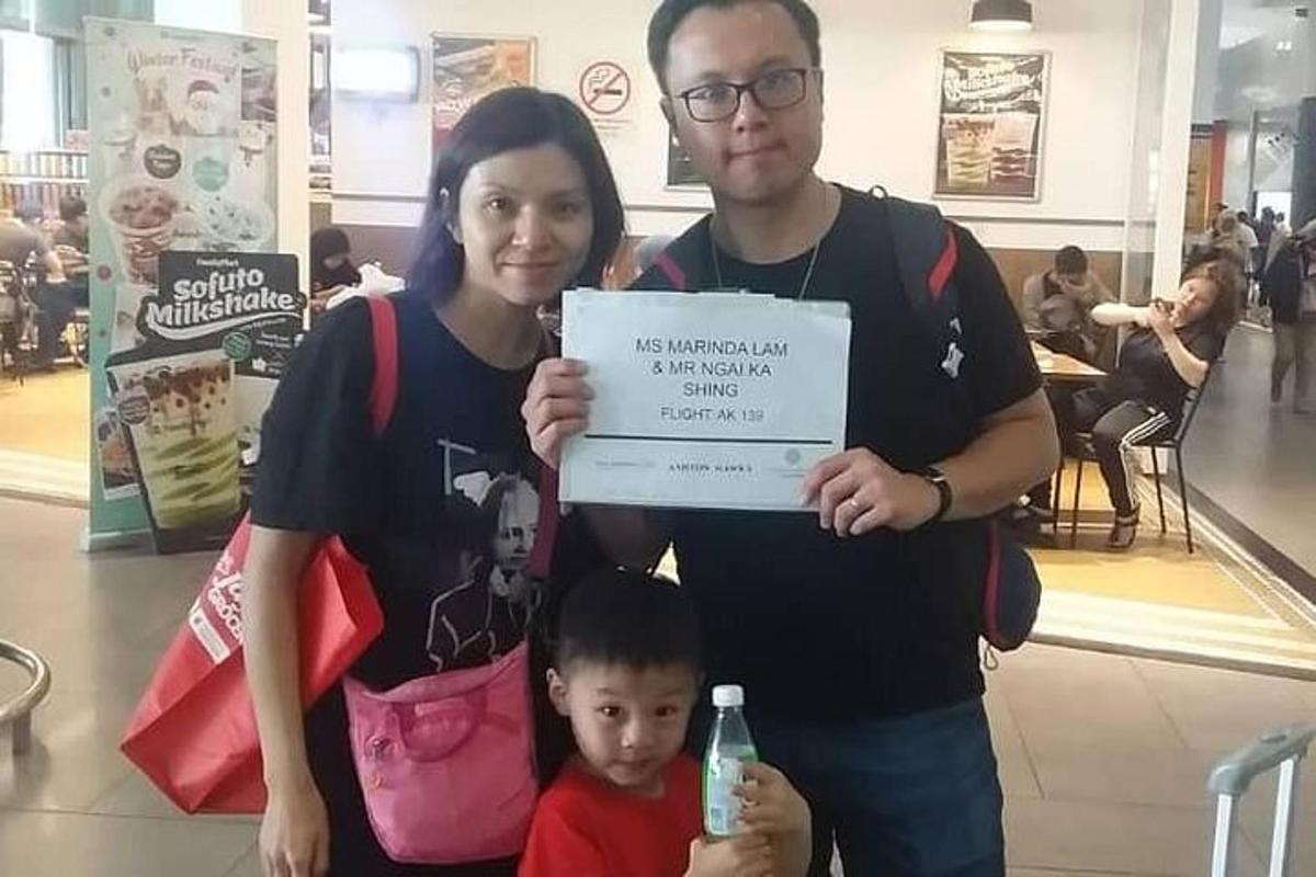 a man and a woman holding a sign with a child