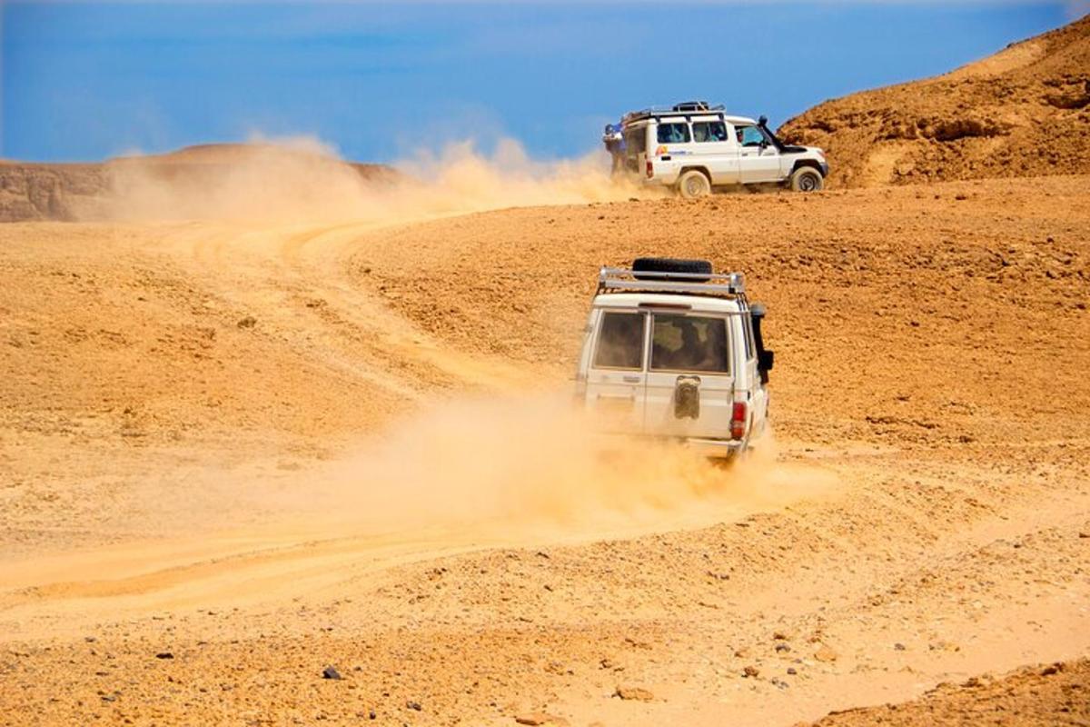 due veicoli che guidano su una strada sterrata nel deserto