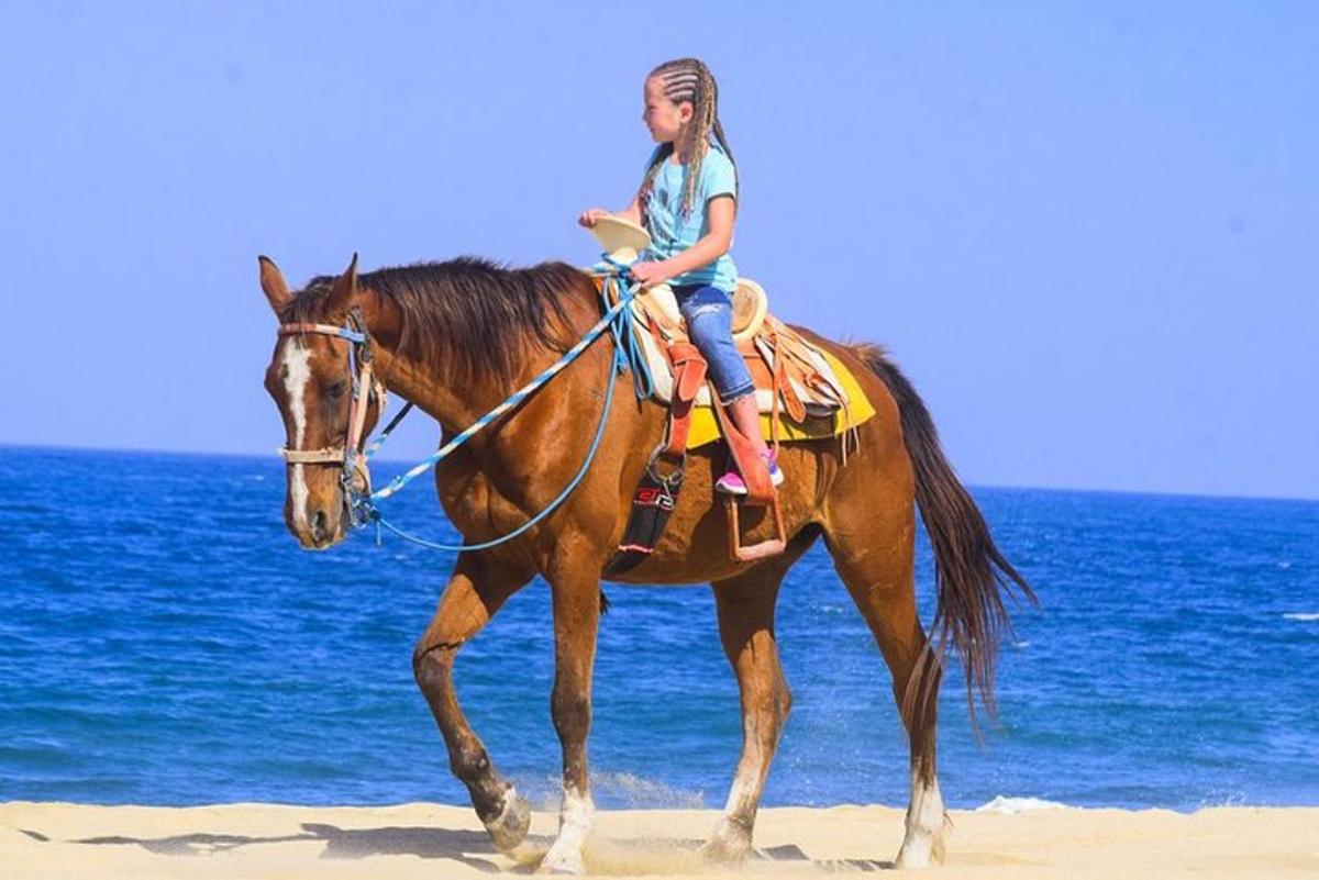 uma jovem cavalgando na praia