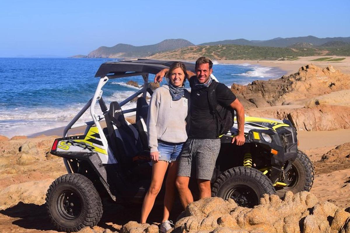un uomo e una donna in piedi accanto a un quad su una spiaggia