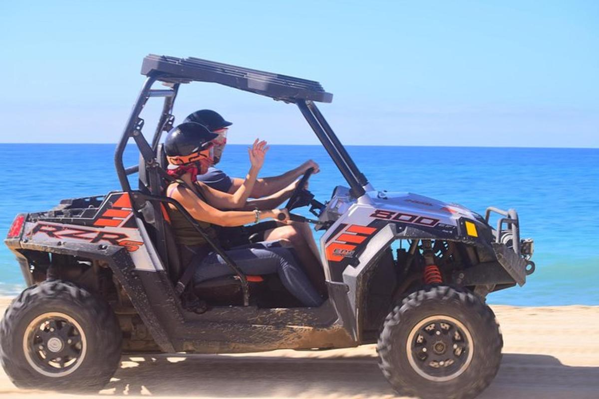 un uomo in sella a un quad sulla spiaggia