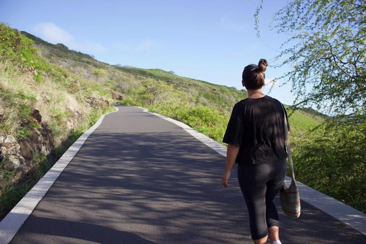 a woman walking down a road with a skateboard