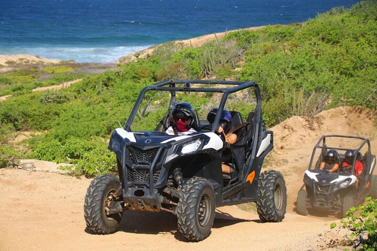 dos quads conduint per un camí de terra prop de l'oceà