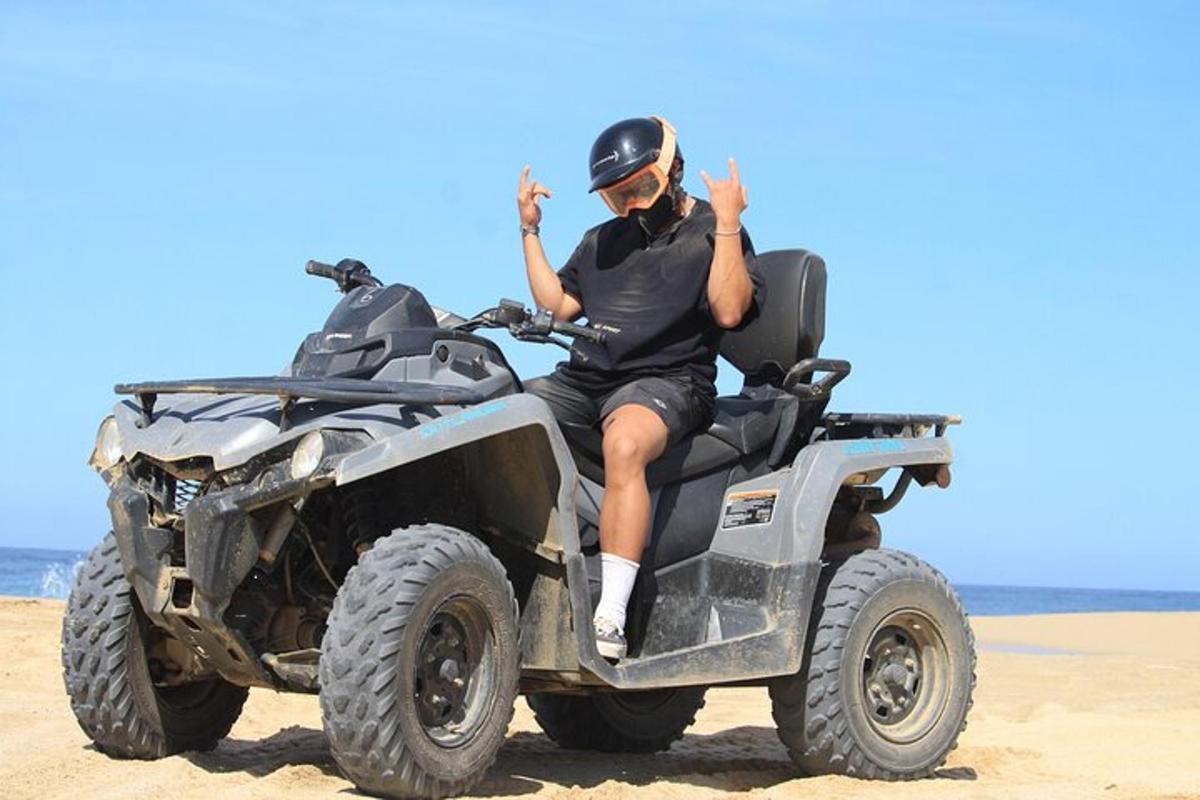 ein Mann sitzt auf einem Geländefahrzeug am Strand