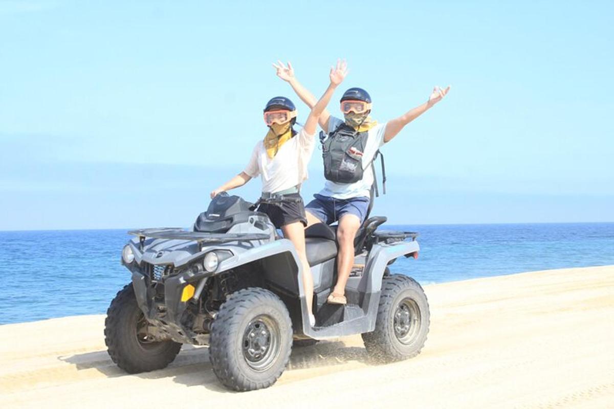 zwei Personen sitzen auf einem Quad am Strand