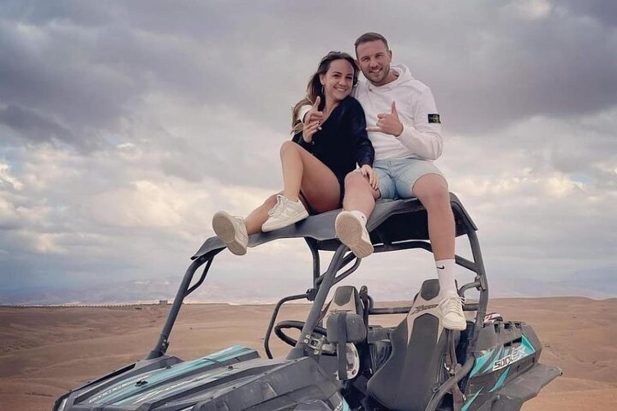 un uomo e una donna seduti sul tetto di un veicolo nel deserto