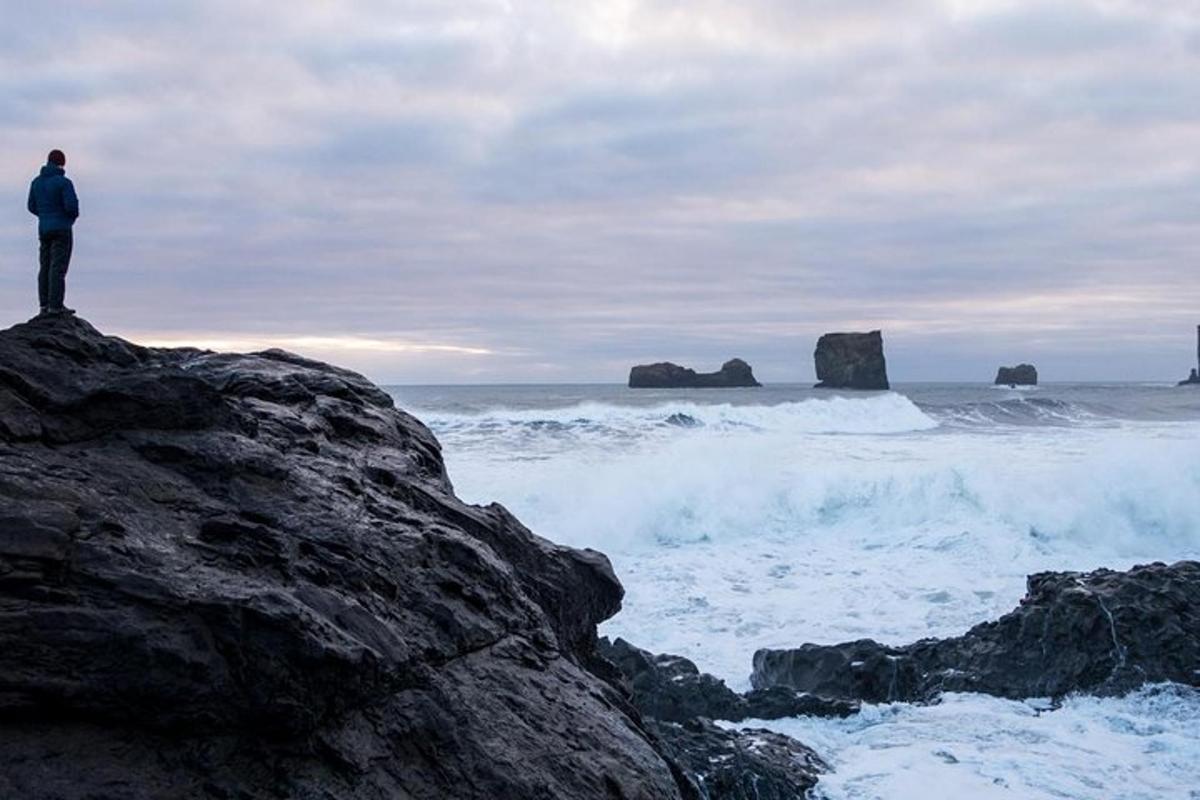 un uomo in piedi su una roccia che guarda l'oceano