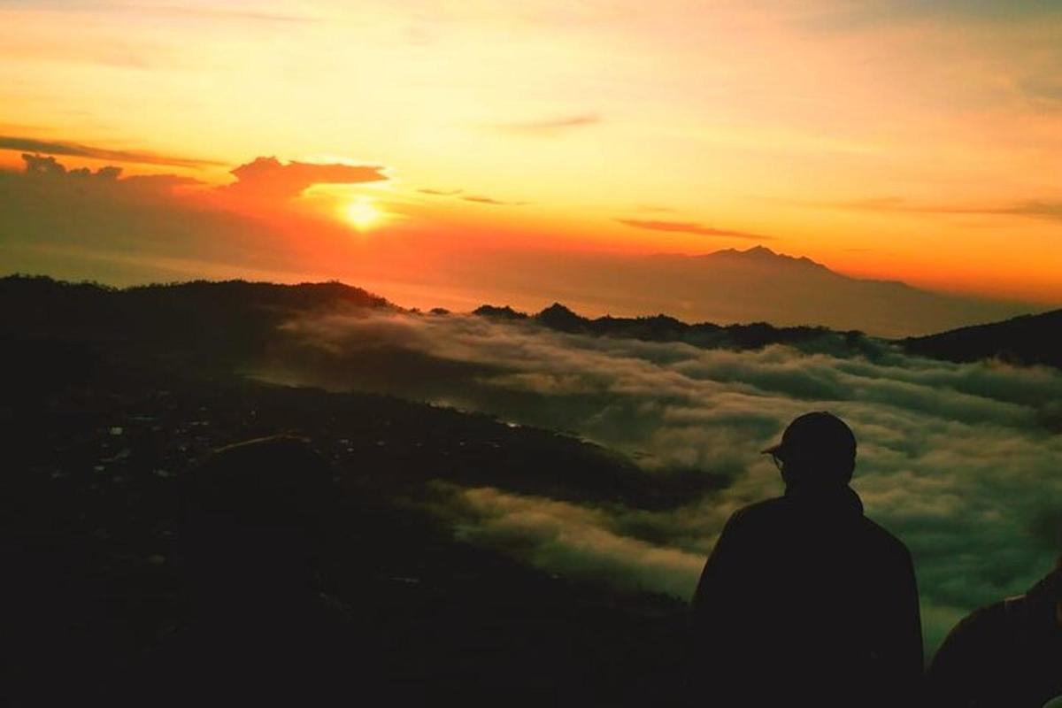 a man standing on top of a mountain watching the sunset