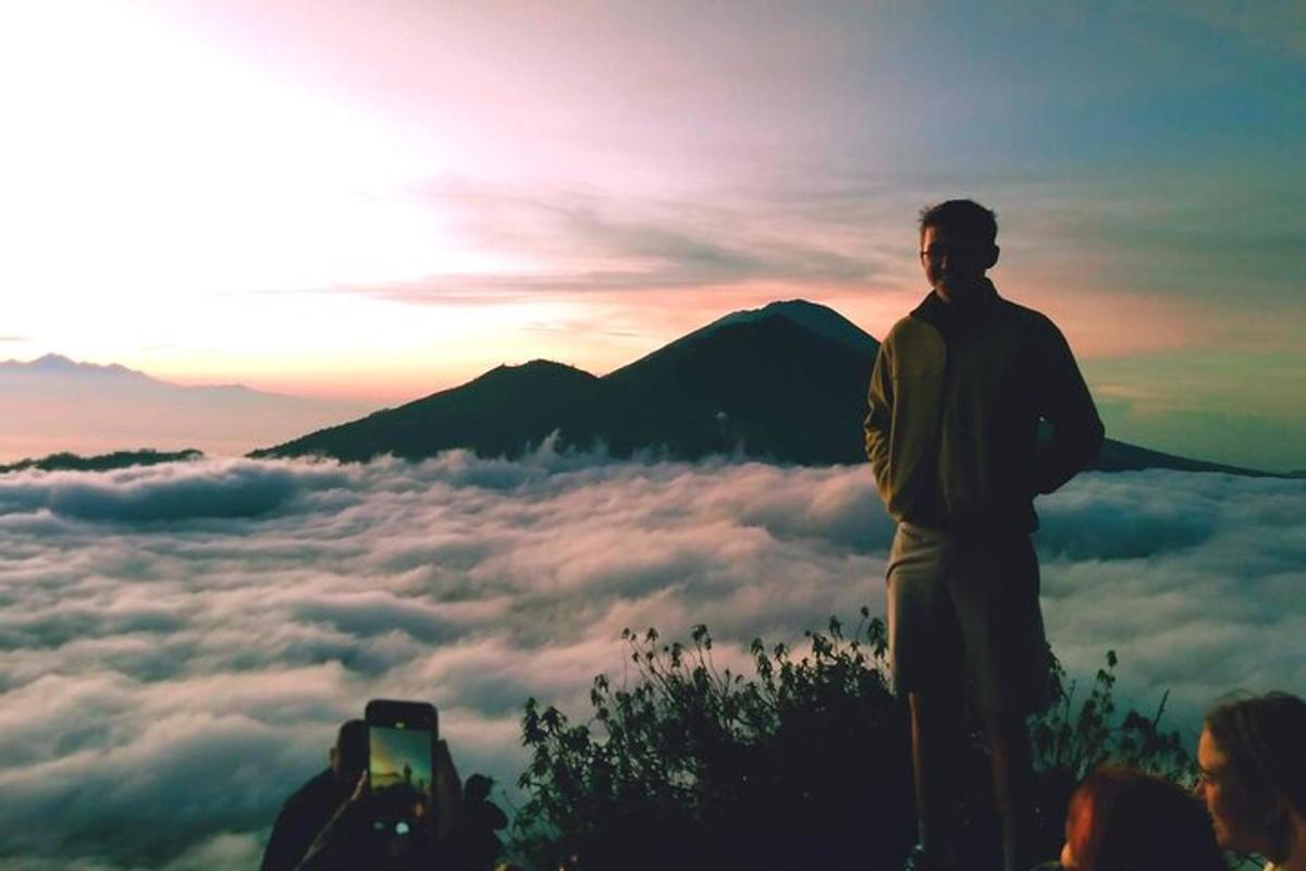 a man standing on top of a mountain with clouds