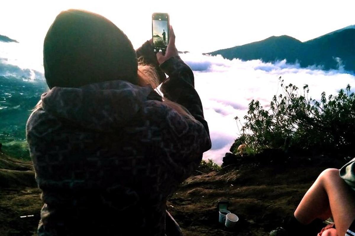 a person taking a picture of a mountain with a cell phone