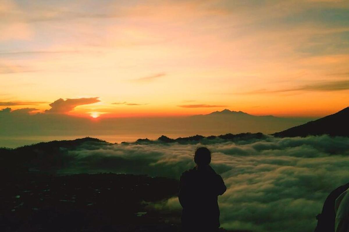 a man standing on top of a mountain watching the sunset
