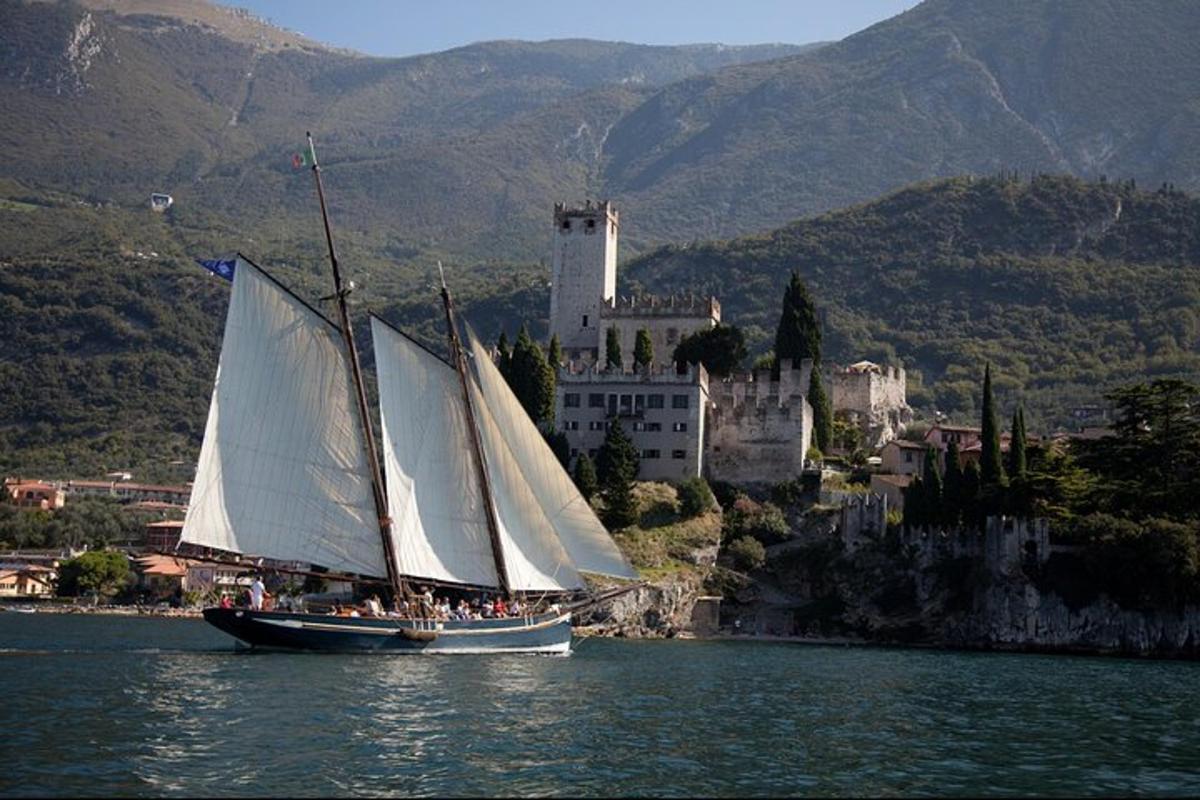 a sail boat in the water in front of a castle