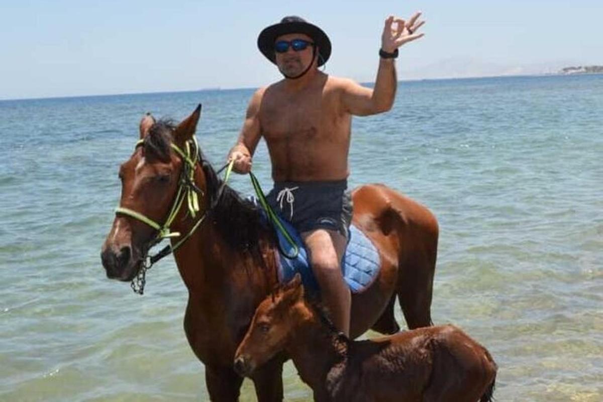en mann som rir på en hest på stranden